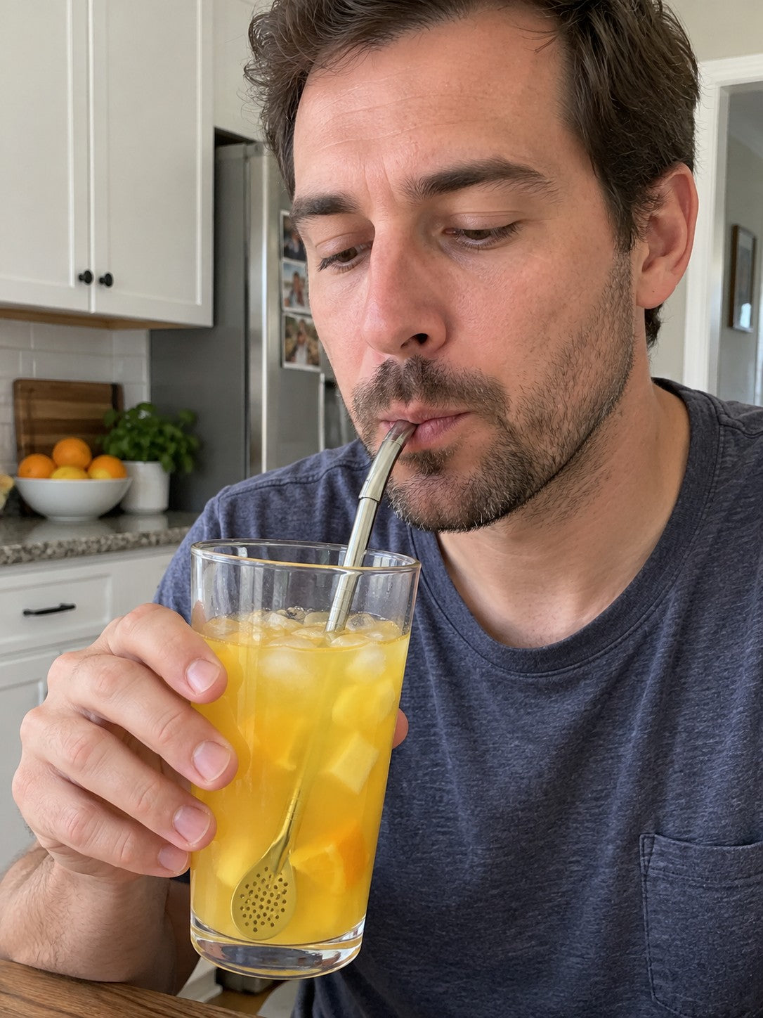 Man sipping orange juice through the gently angled metal tip