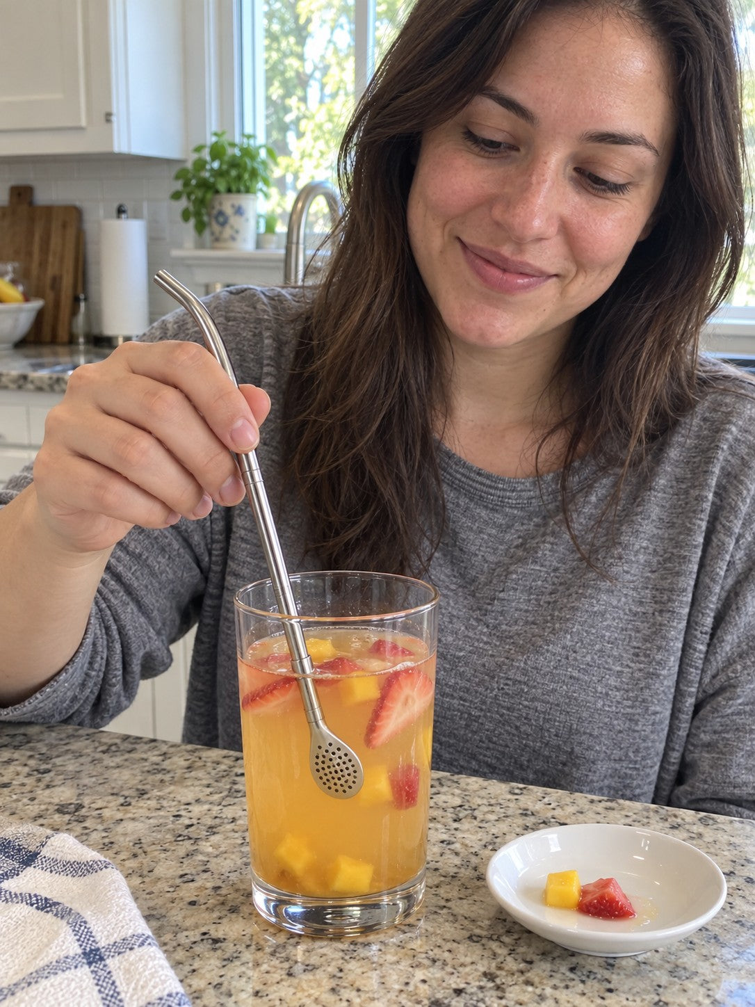 Woman stirring mango and strawberry juice with the spoon straw