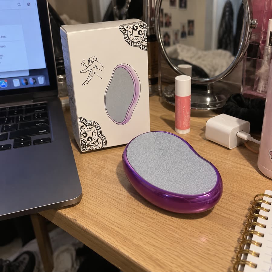Purple crystal hair eraser on a desk beside packaging and beauty items