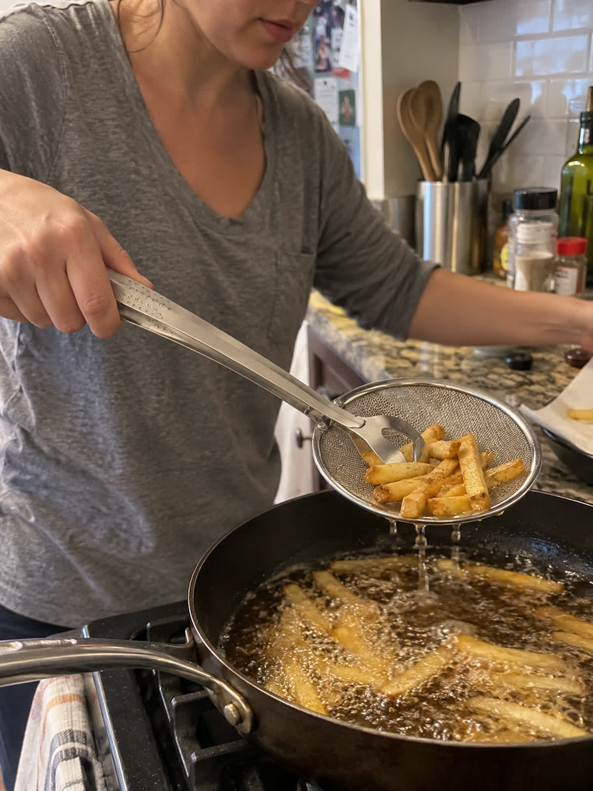 Customer using spider strainer tongs in a home kitchen