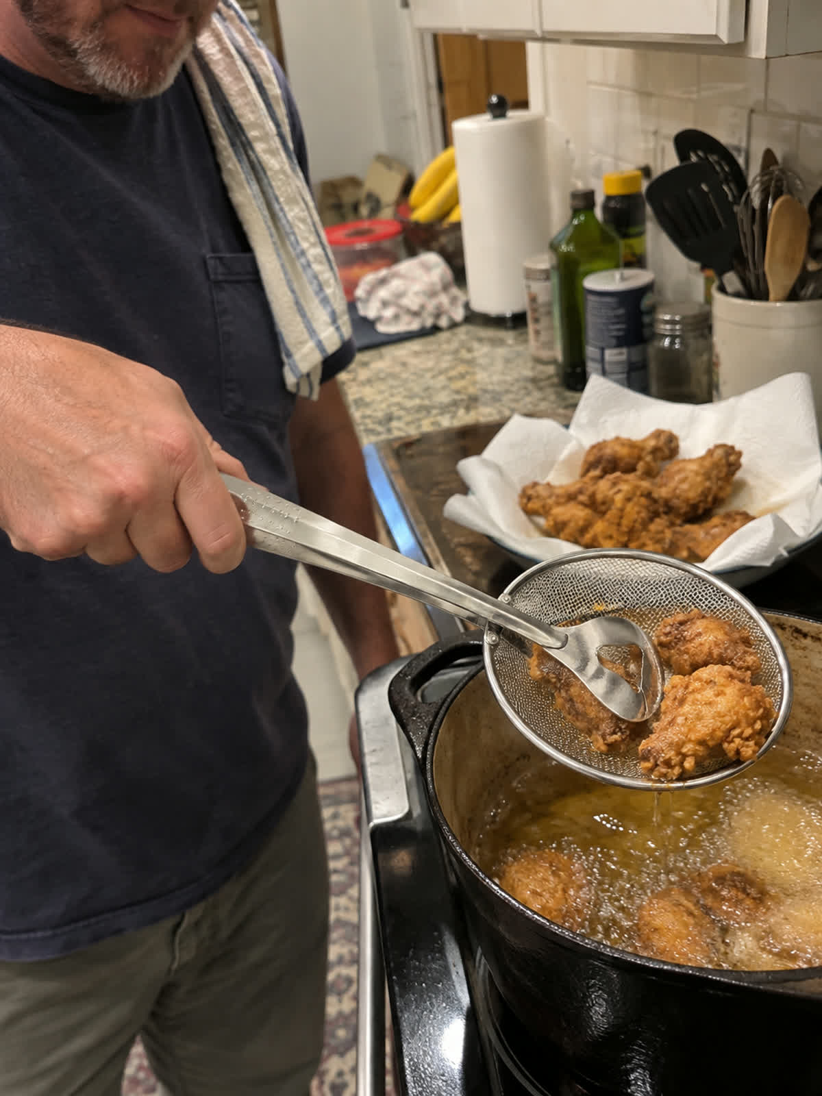 Customer using spider strainer tongs in a home kitchen