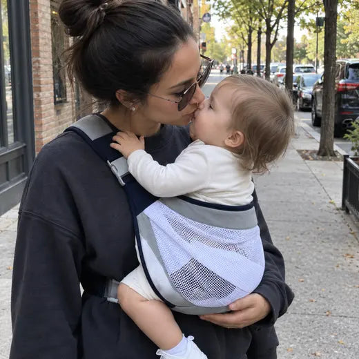 Mother wearing the mesh baby sling carrier on a city sidewalk