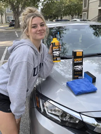 Customer holding car coating spray on a silver car hood
