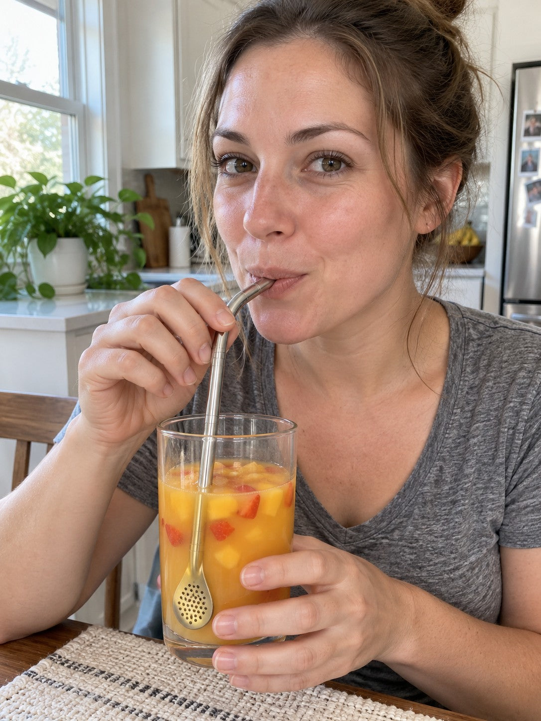 Woman sipping mango and strawberry juice through the curved metal tip