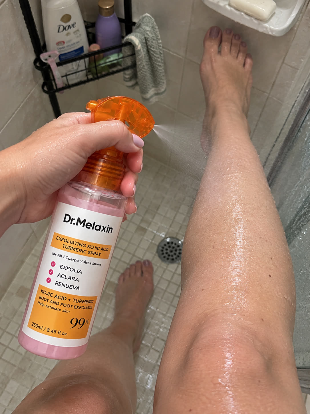 Customer applying body exfoliating spray to legs in the shower