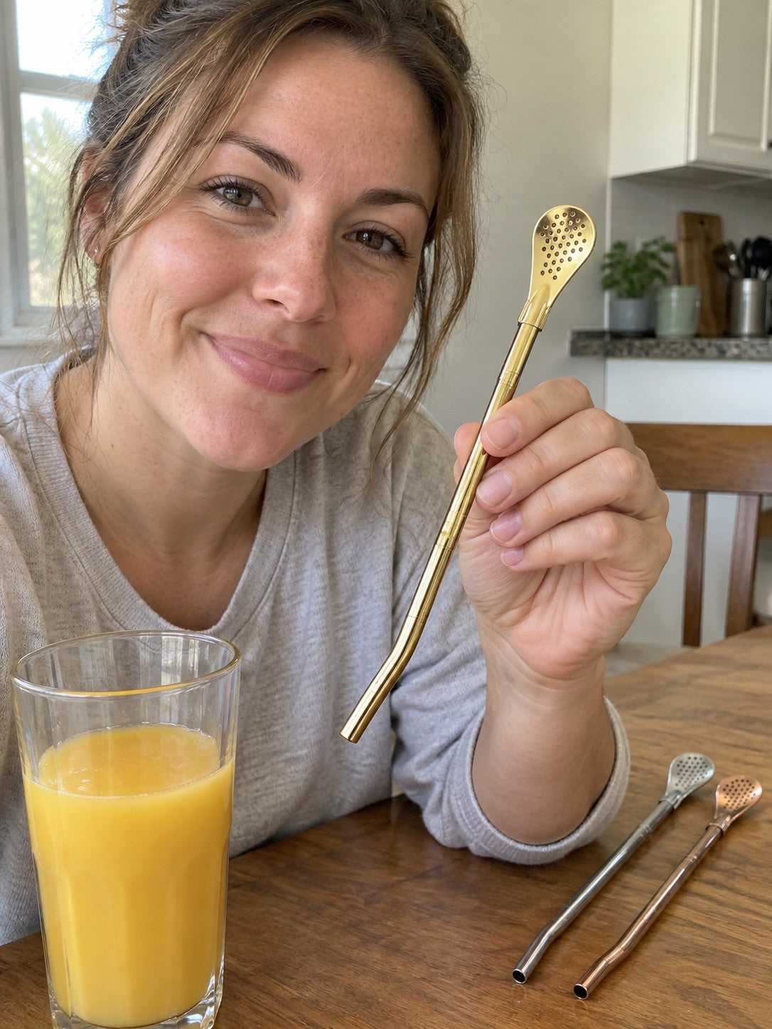 Woman showing a gold spoon straw beside silver and rose gold finishes
