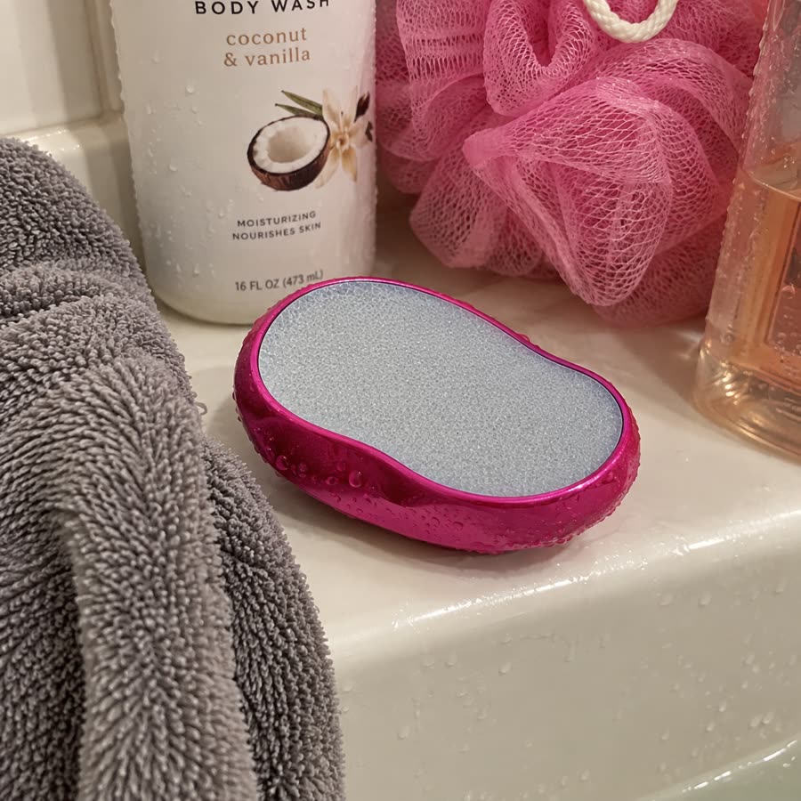 Pink crystal hair eraser with water droplets on a shower ledge
