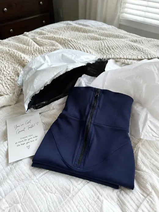 Folded blue leggings with package and thank you card on a bed