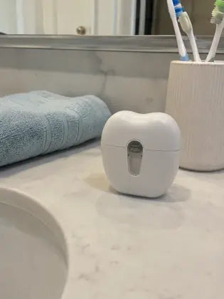 Electric nail clipper stored on a clean bathroom vanity