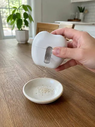 Electric nail clipper emptying collected nail debris into a small bowl