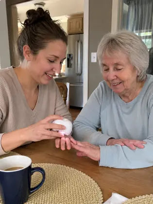 Adult daughter helping an elderly mother trim nails with an electric nail clipper