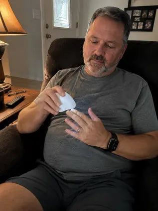Man using an electric nail clipper while sitting in a living room chair