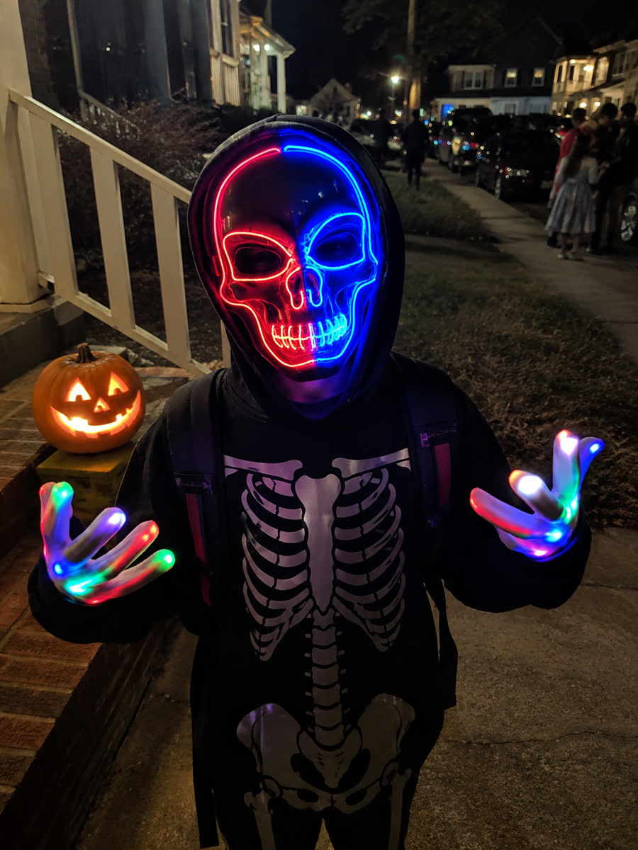Child wearing the LED glow skull mask and light-up gloves for trick-or-treat night