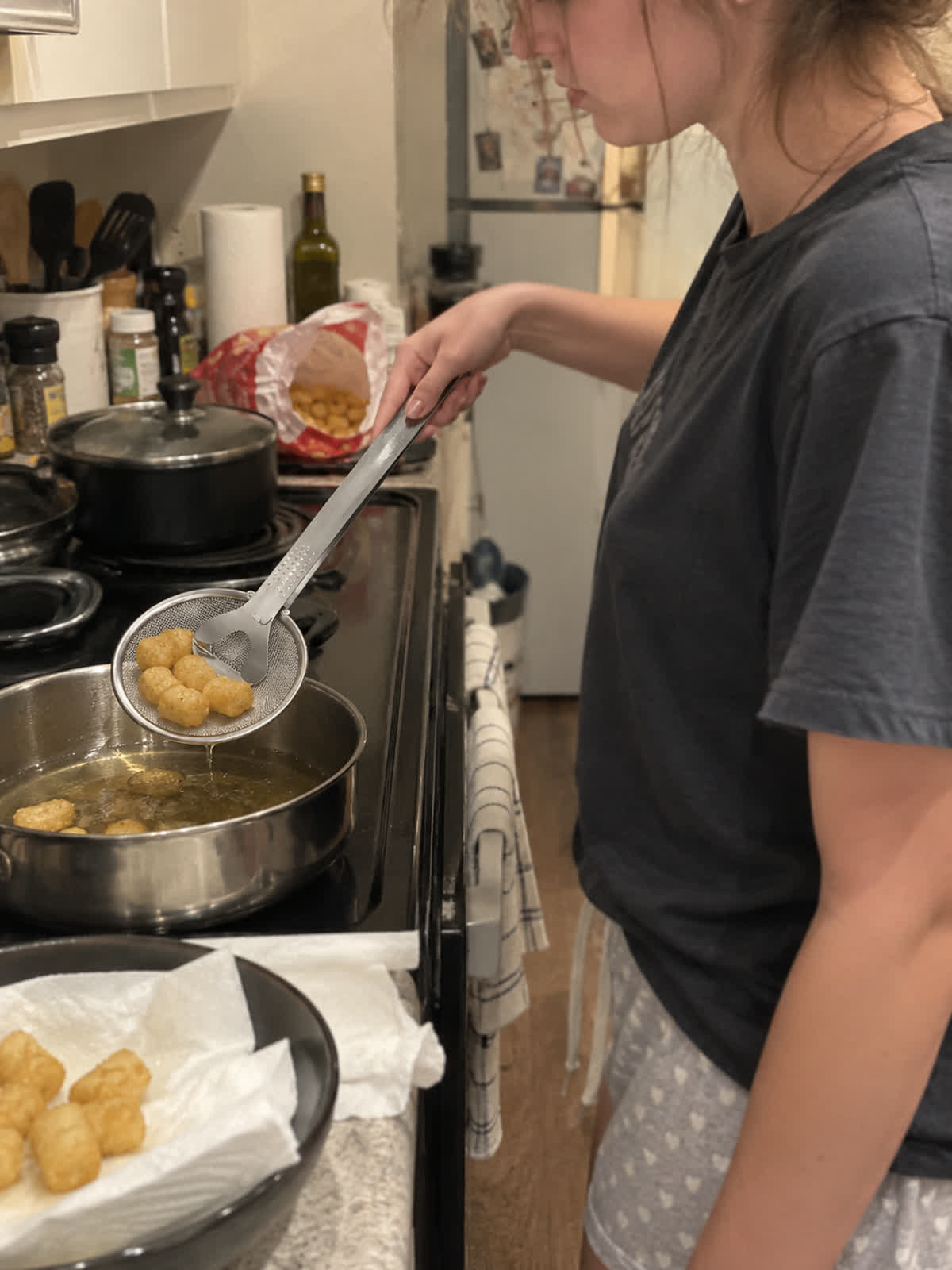 Customer using spider strainer tongs in a home kitchen