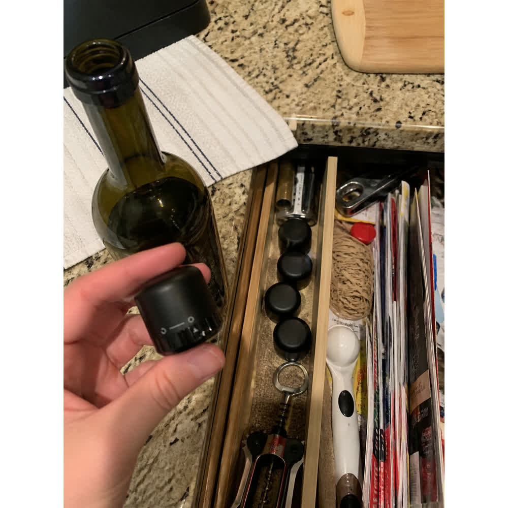 Compact black wine stoppers stored in a kitchen drawer next to a wine opener
